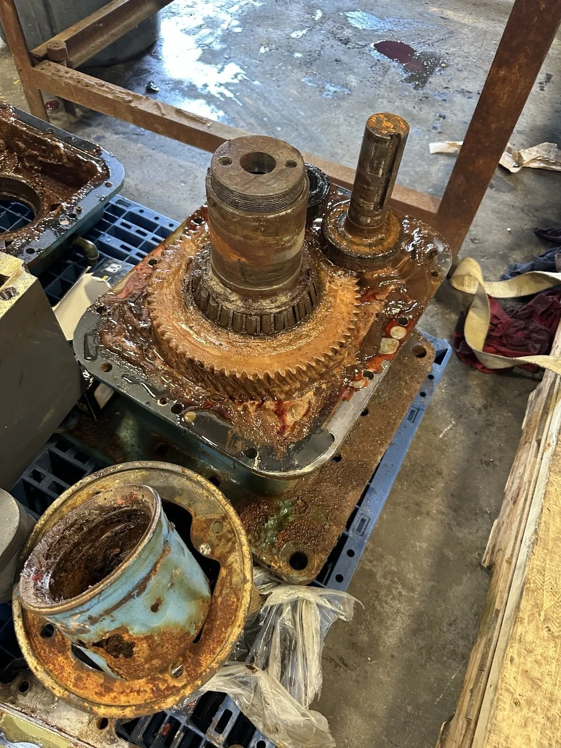 Exposed gear assembly with visible corrosion; removed housing components sit alongside.