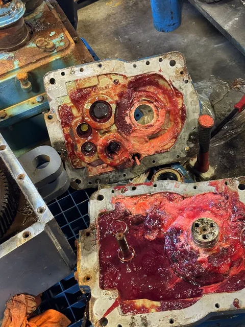 Gearbox housing sections with bearing openings, deposits and discolored interior surfaces.