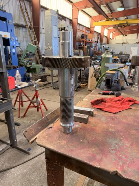 Long shaft carrying a large helical gear and a smaller pinion section.