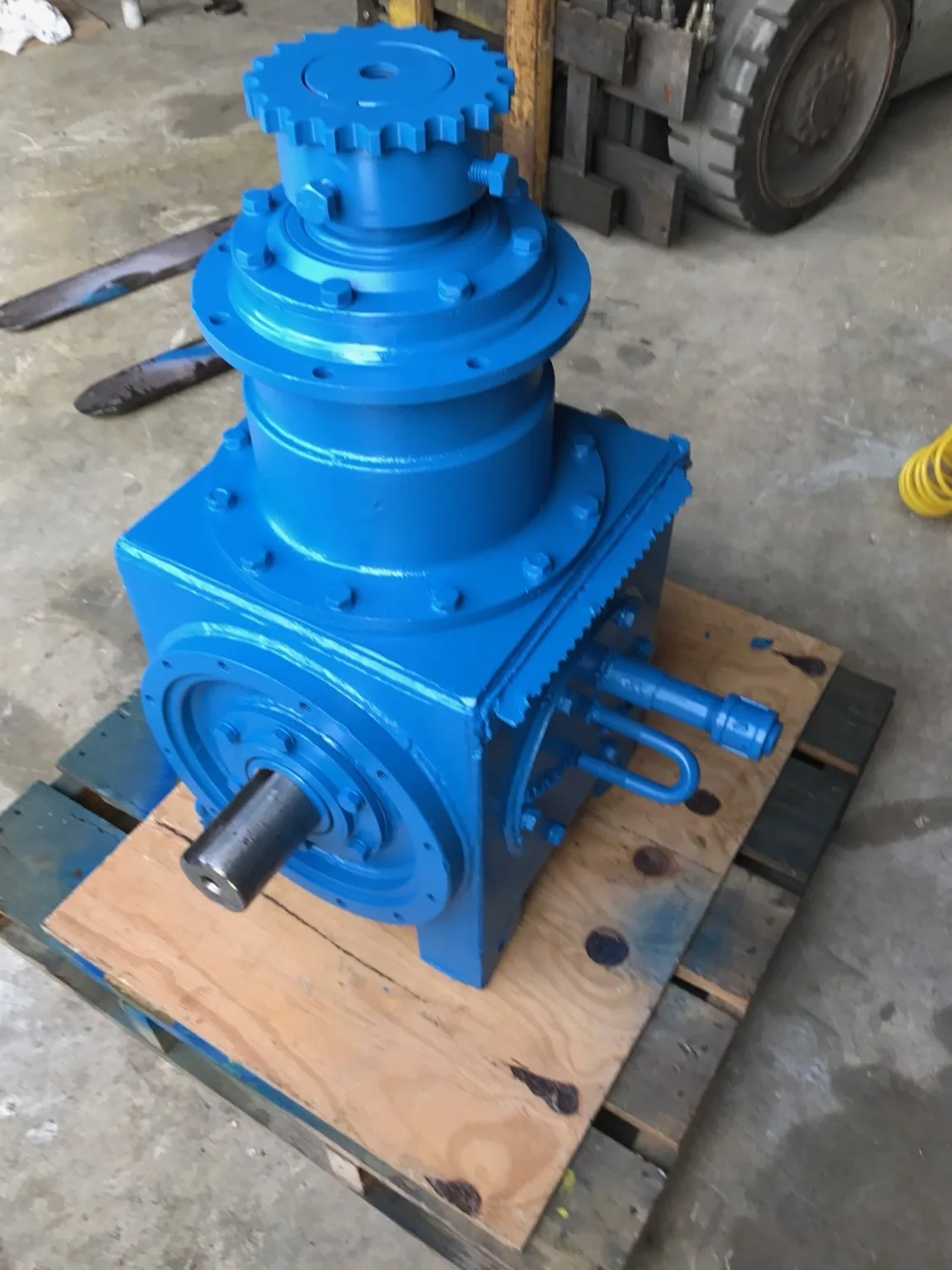 Assembled gearbox on a pallet, with a projecting shaft and top-mounted sprocket.